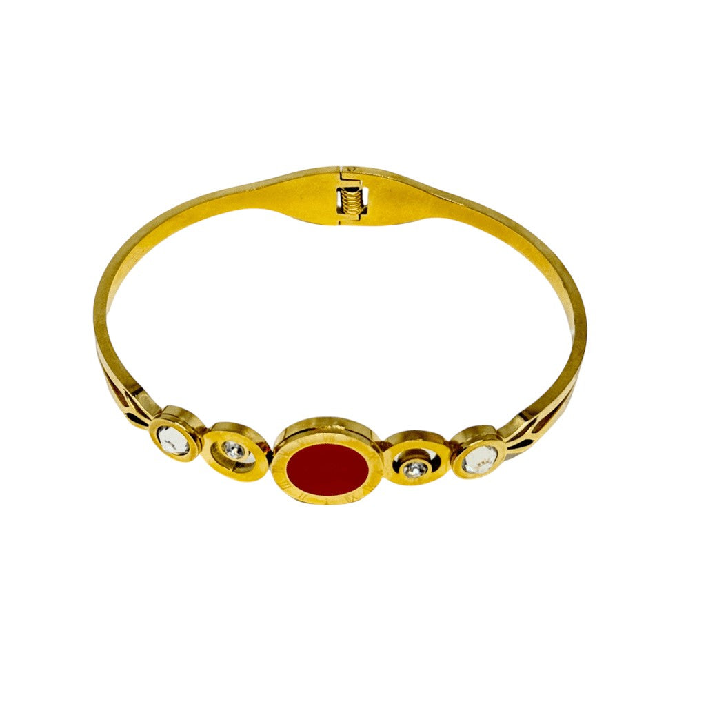Gold bracelet with a red stone and clear stones on a white background