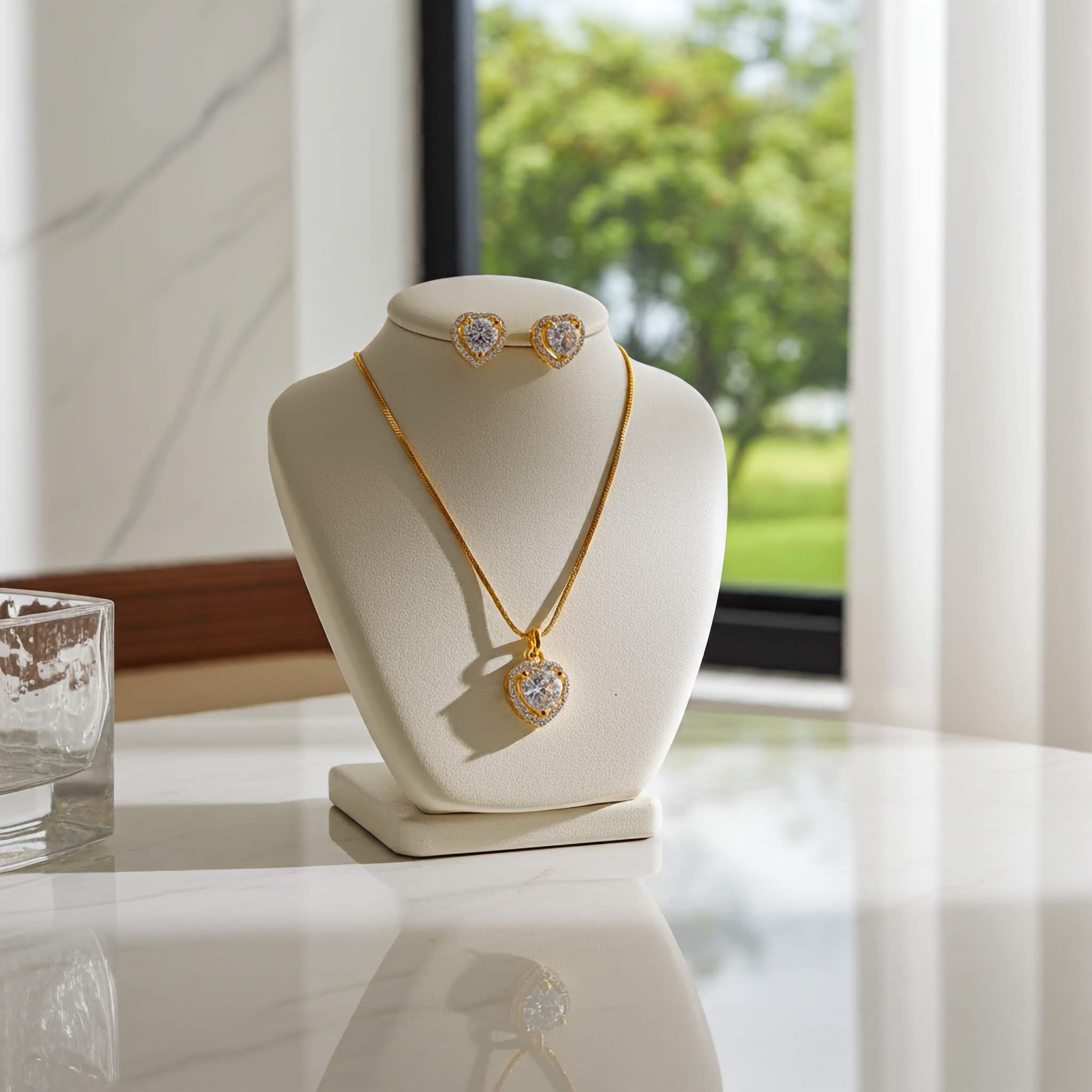 Zirconia 18k Gold plated necklace and earrings on a white mannequin bust with a blurred outdoor background