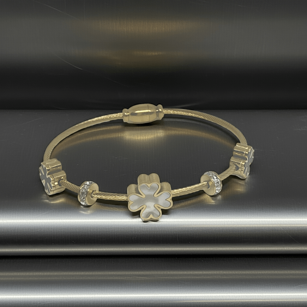 3 leaf charm bracelet with 18k gold plating  on top of a metal counter top 