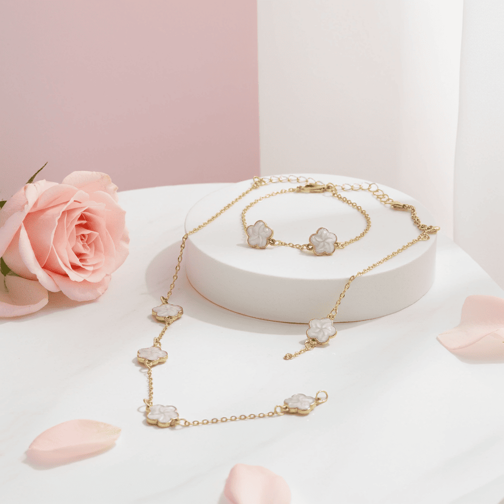 Gold necklace with 5 flowers white clovar pendants on a white stand with pink roses and petals.