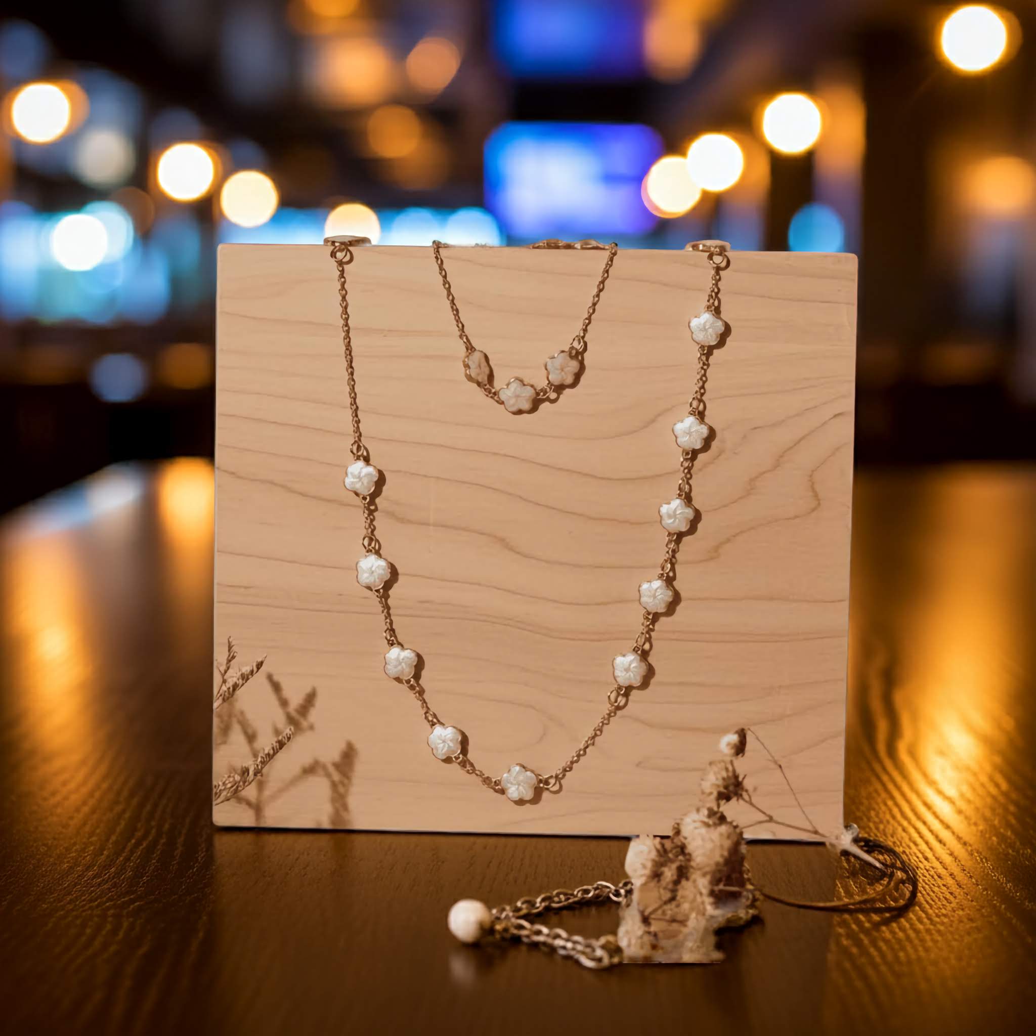 white clover Necklace and bracelet with on a wooden stand against a blurred background with lights.
