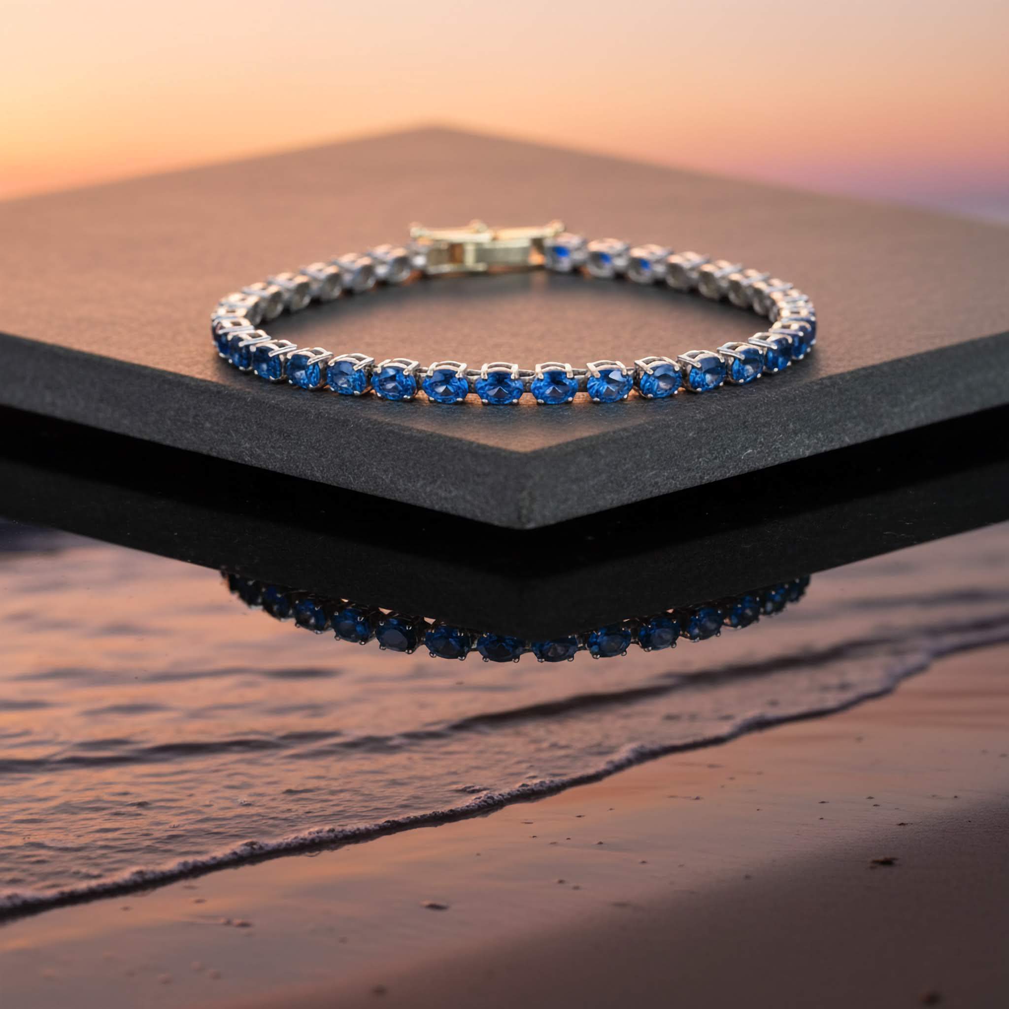 Luxury Statement Jewelry Bracelets collection Blue gemstone bracelet on a black stand with a sunset beach background
