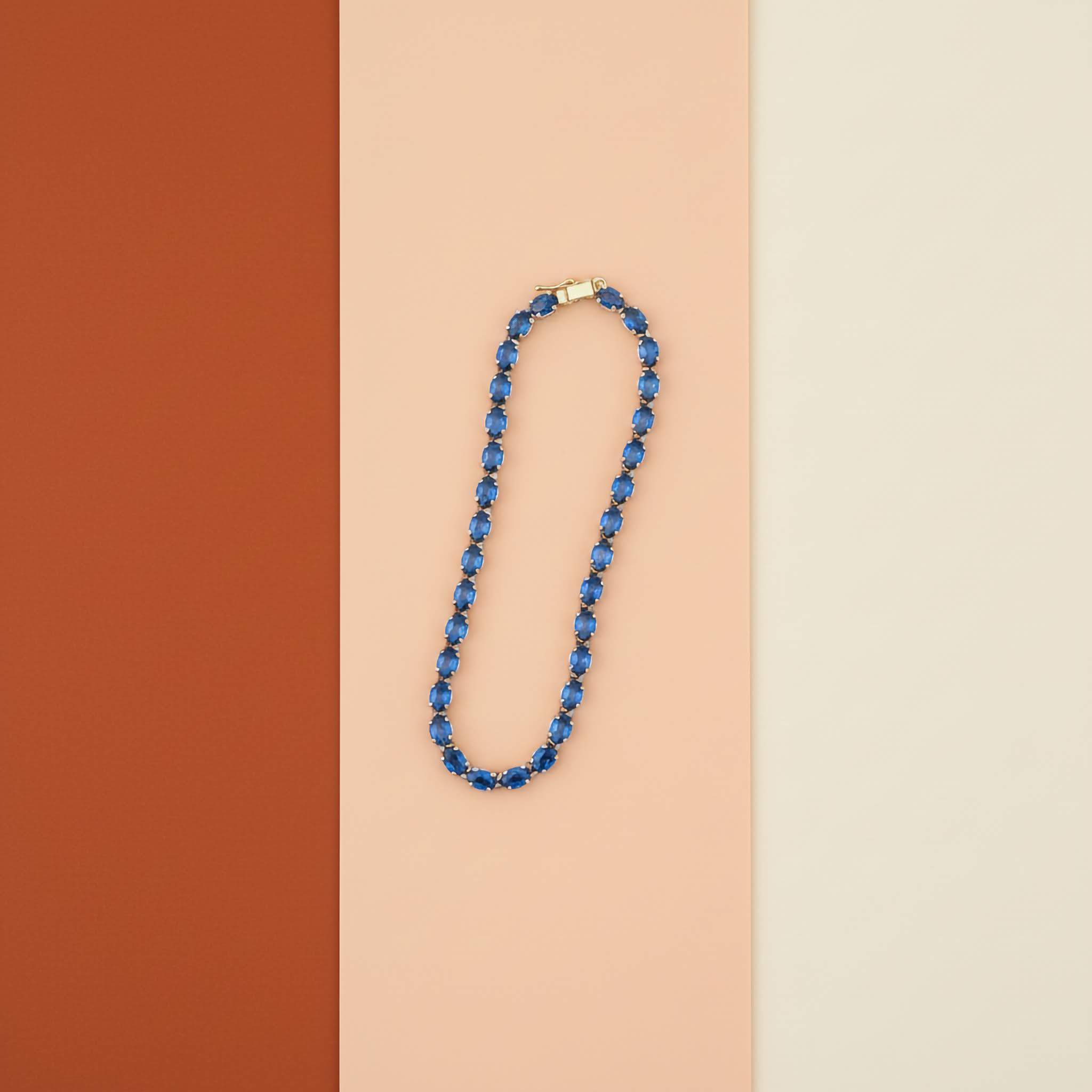 Luxury Statement Jewelry Bracelets Collection Blue tennis bracelet on a two-tone brown and beige background