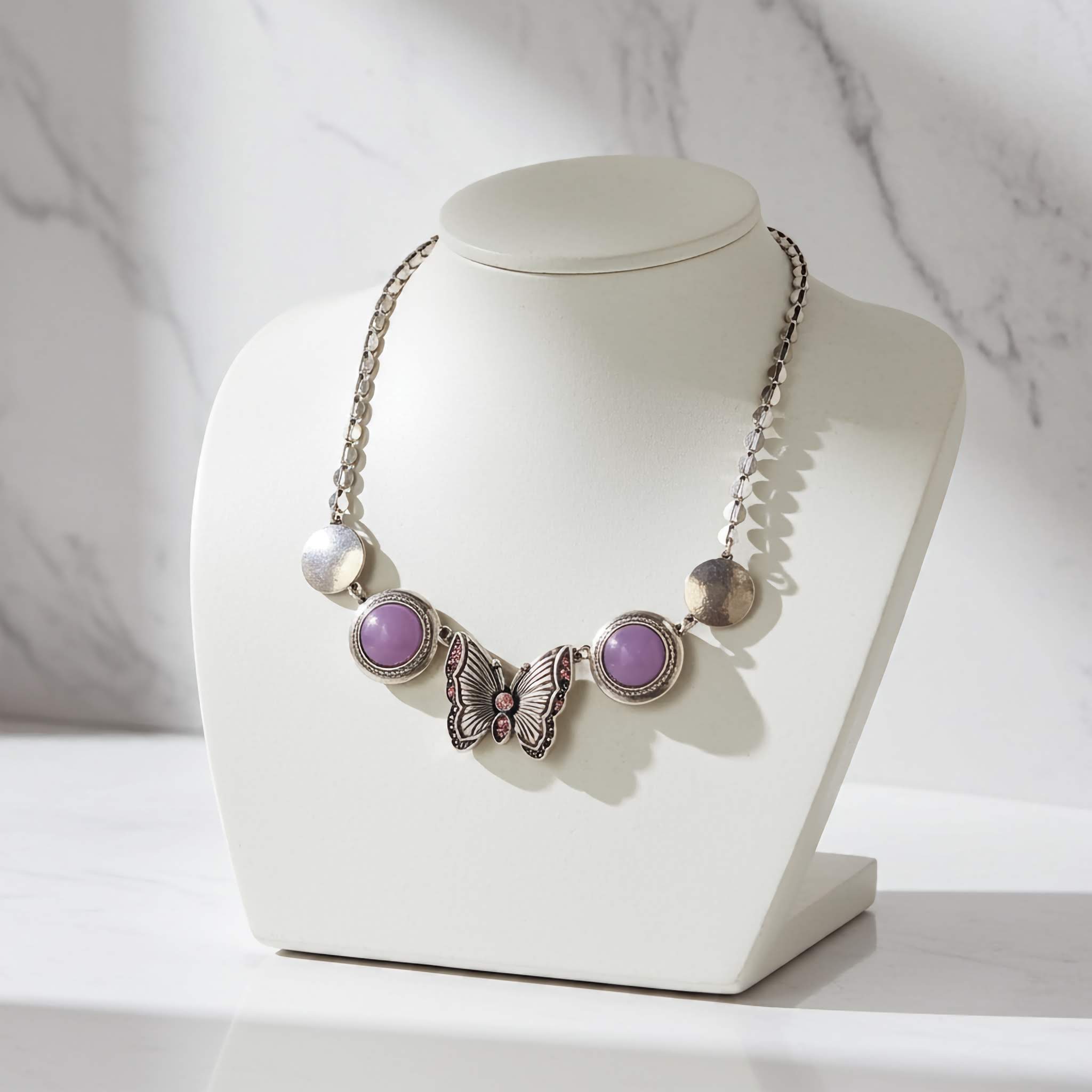 A german silver Necklace with butterfly and purple gemstone design on a white mannequin bust against a marble background. offered by LeDeSaRa @ $10.