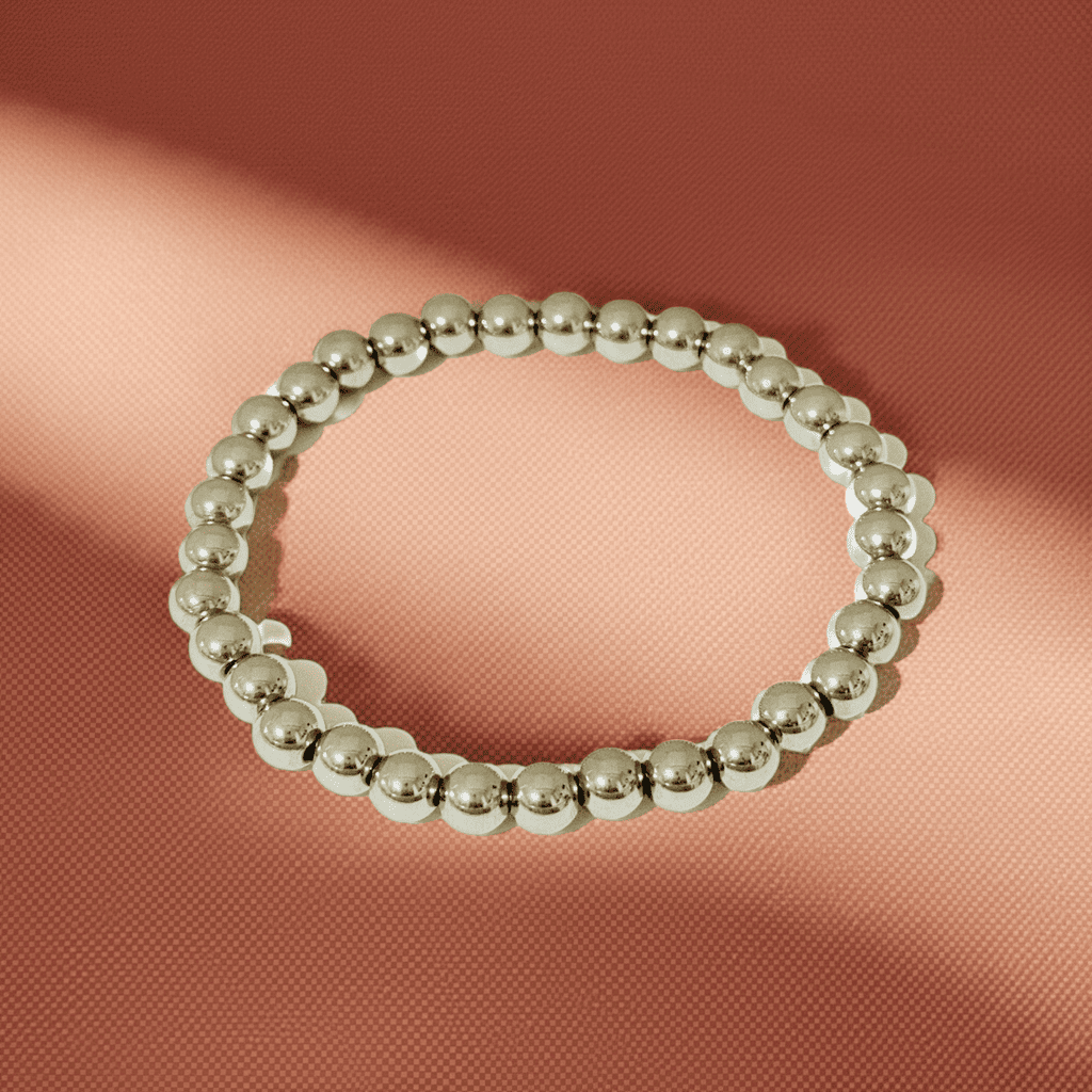 Silver beaded slip-on bracelet on a pink fabric background