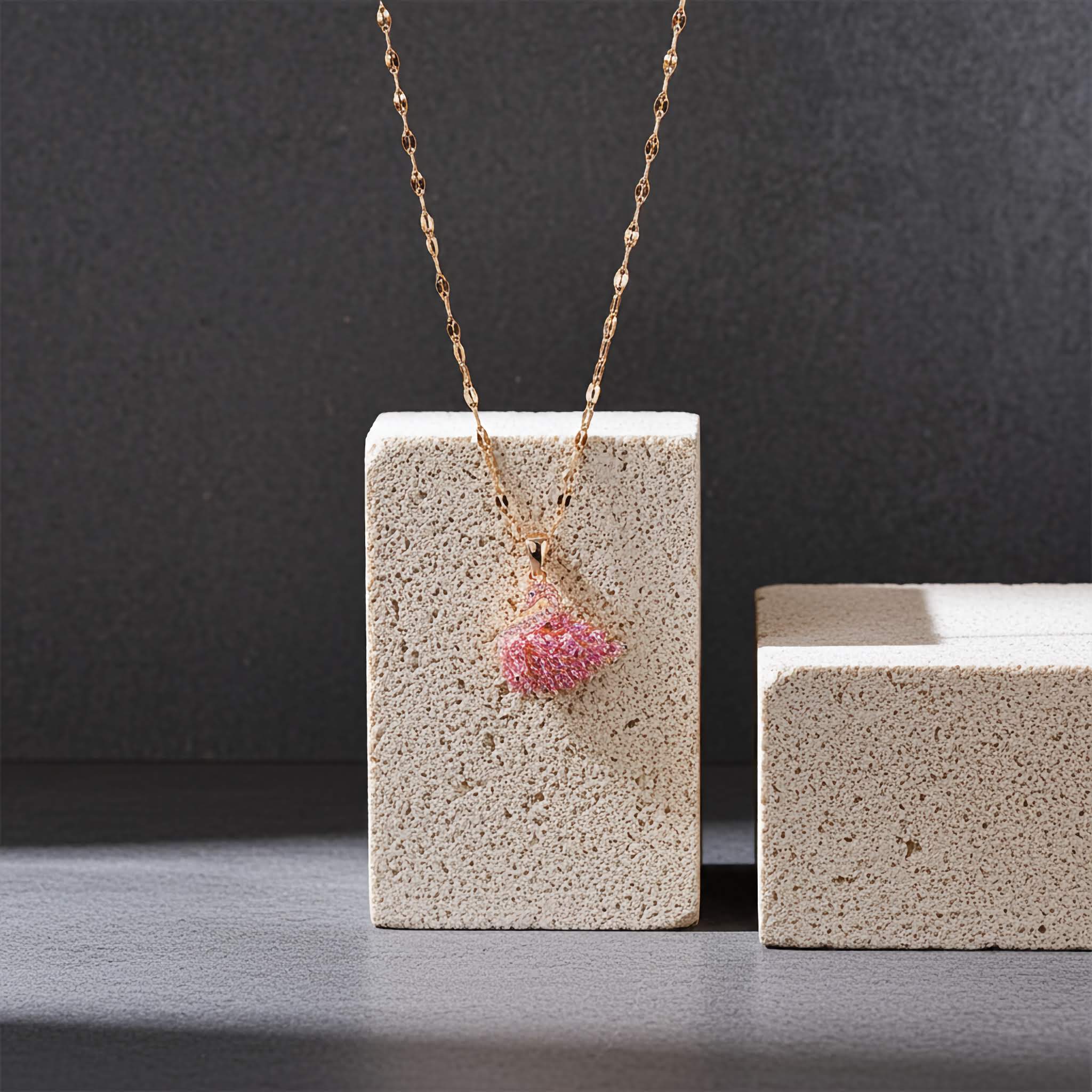 Crystal Necklace with a pink pendant on a textured block against a dark background