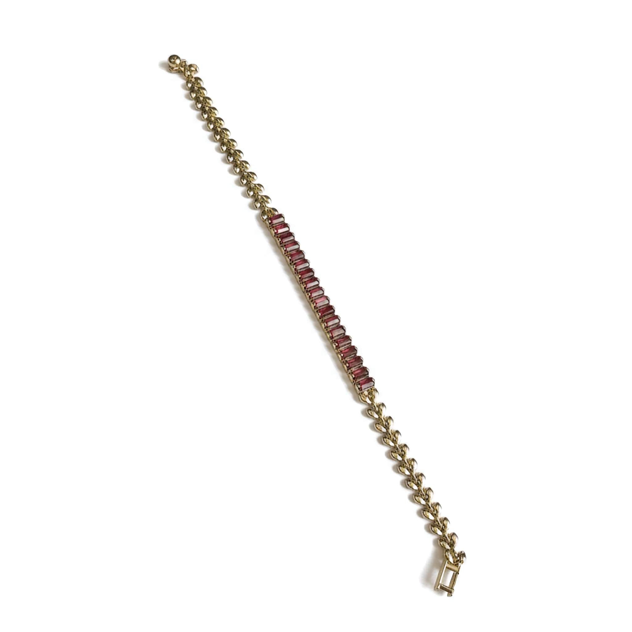 Gold chain bracelet with red gemstones on a white background