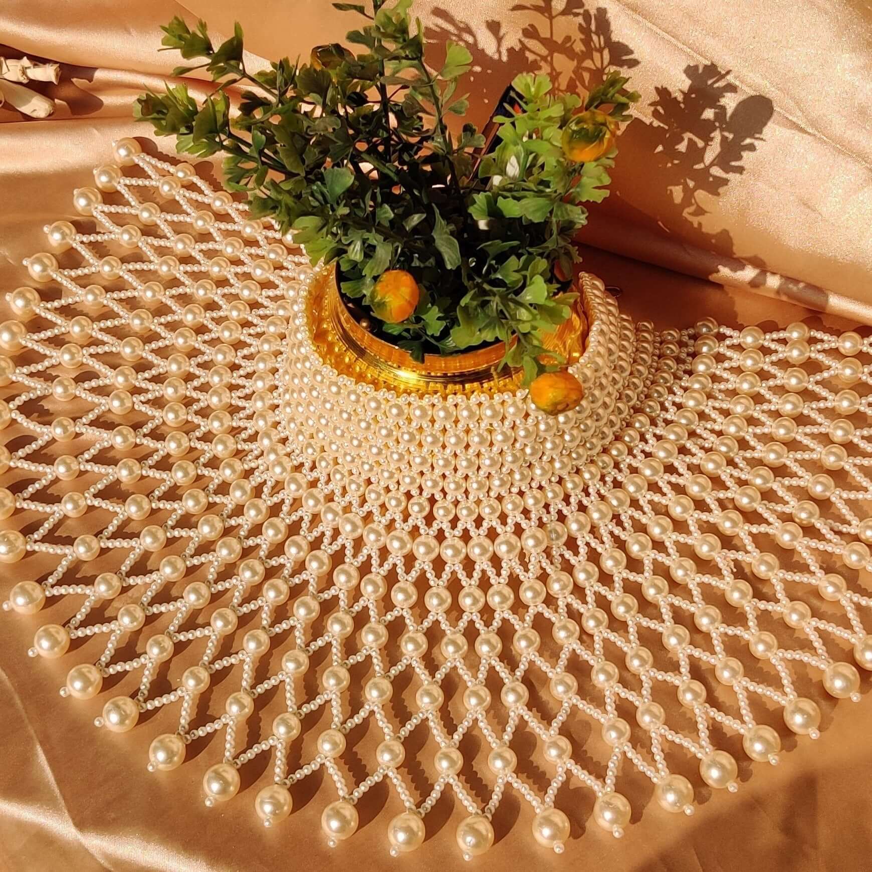 The Kavita Pearl Necklace displayed elegantly on a soft fabric backdrop with a decorative plant.