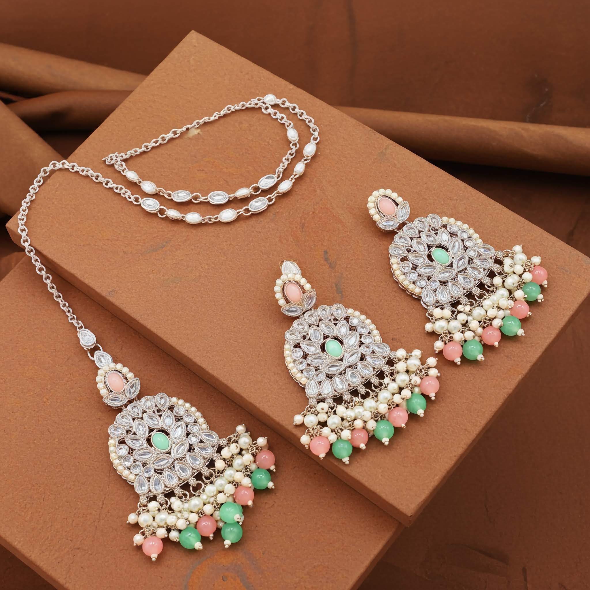 Mirror designed earrings and tikka set pink and ferozi Jewelry set with necklace and earrings on a brown surface