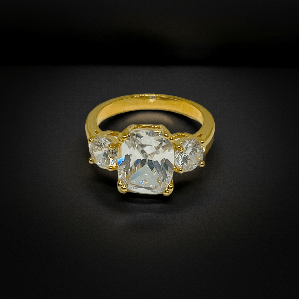 Gold ring with a central diamond and two side stones on a black background
