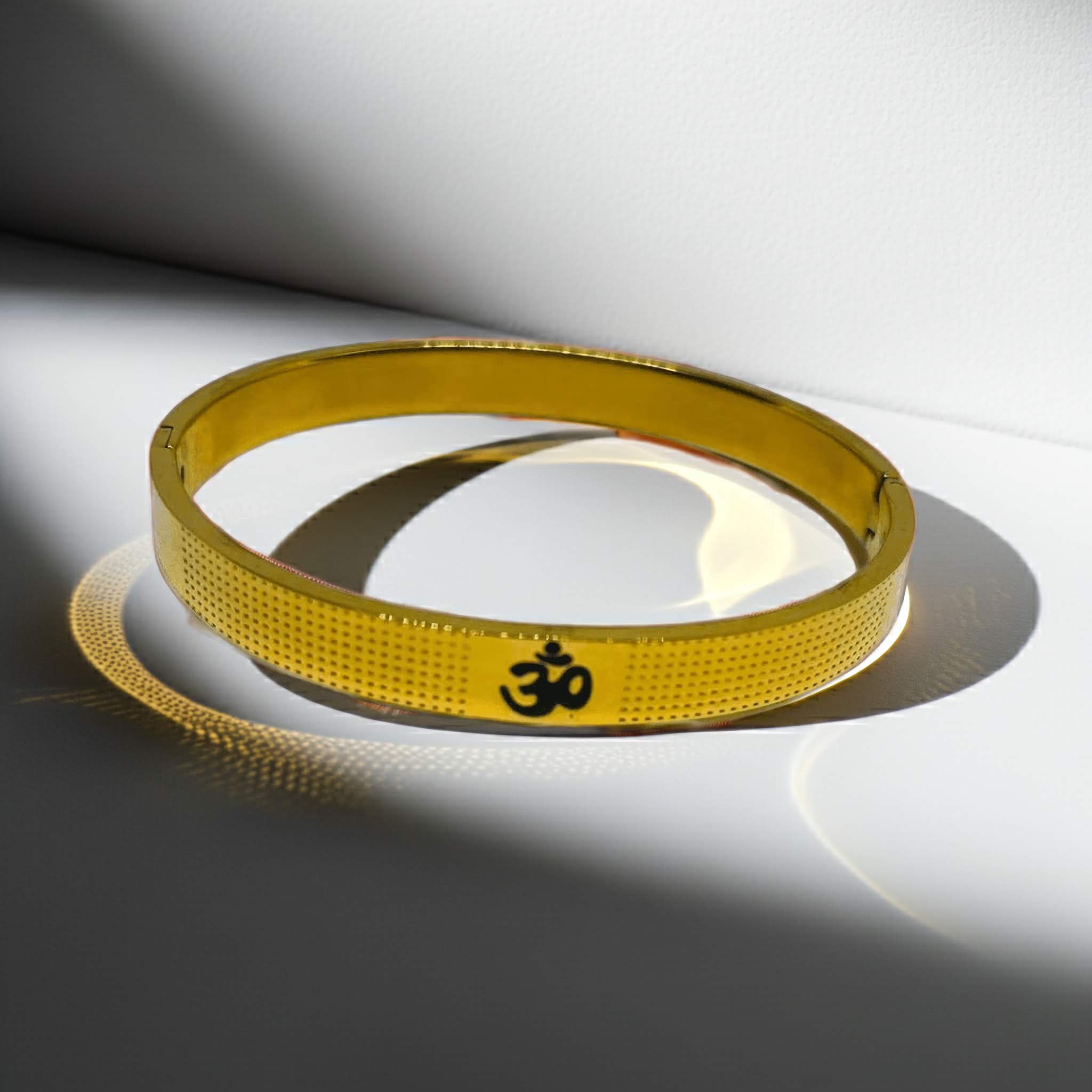 Gold bracelet with a hindu Om symbol on a white background