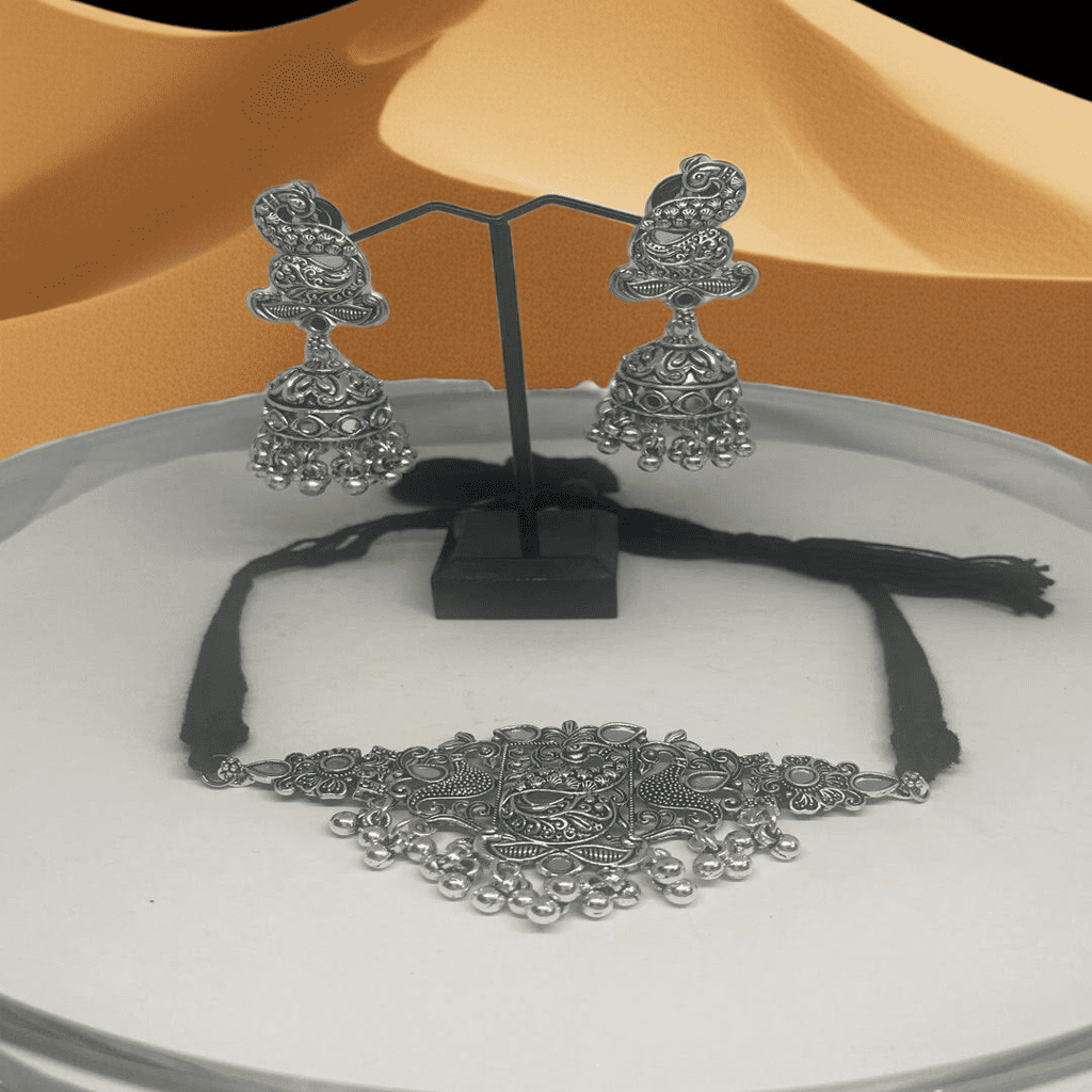 oxidized Silver jewelry set including earrings and a necklace on a white surface with a black stand.