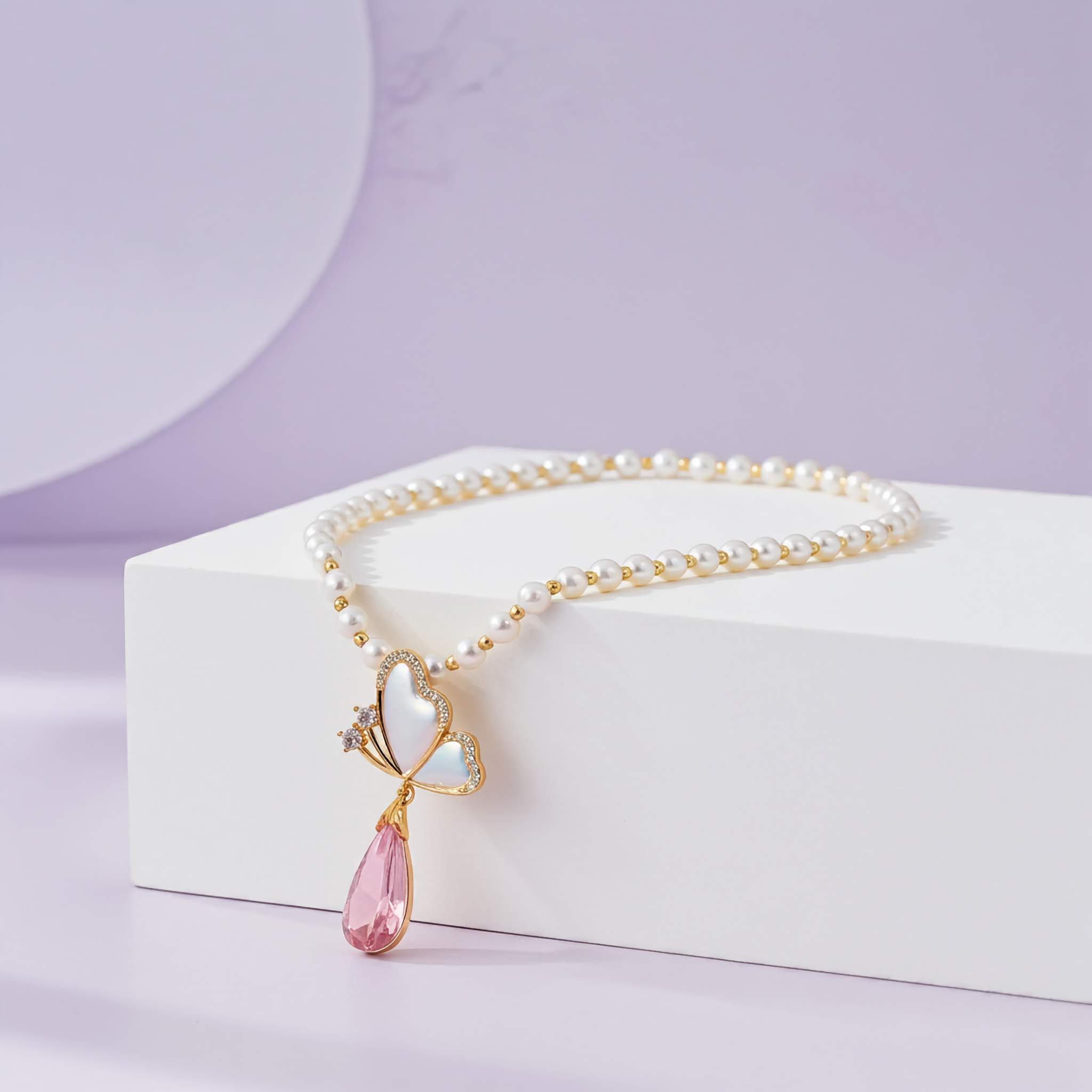 Pearl necklace with a pink teardrop pendant on a white stand against a light purple background