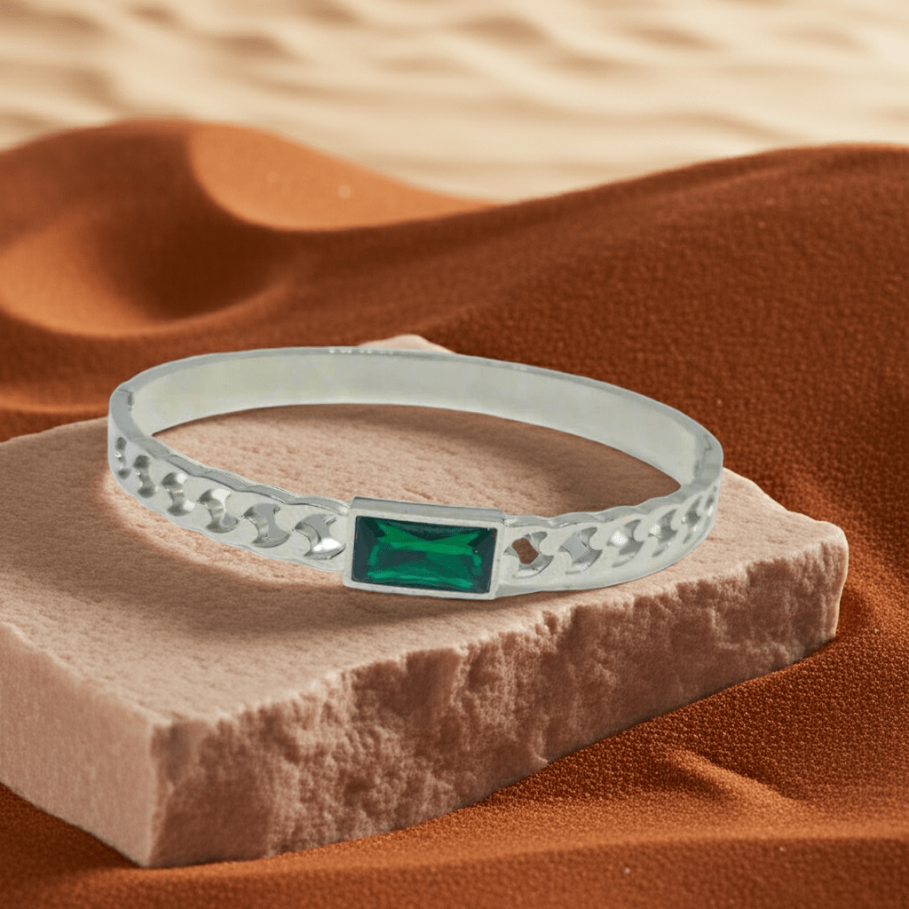 Silver bracelet with a green gemstone on a textured surface