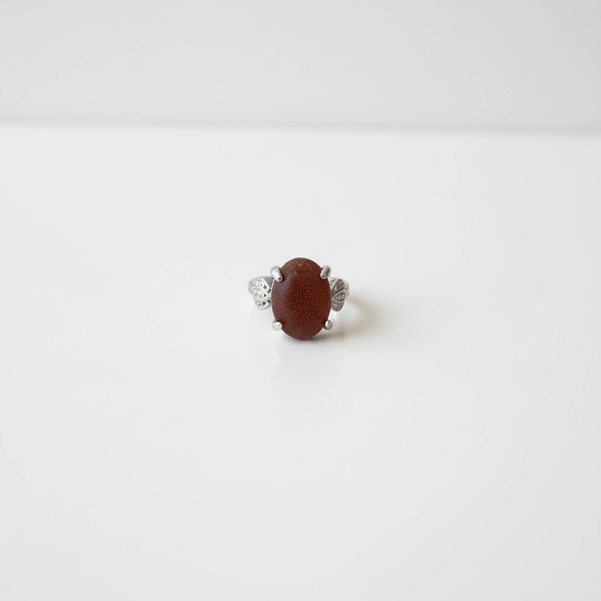 Silver ring with a brown sparkly gemstone on a white background