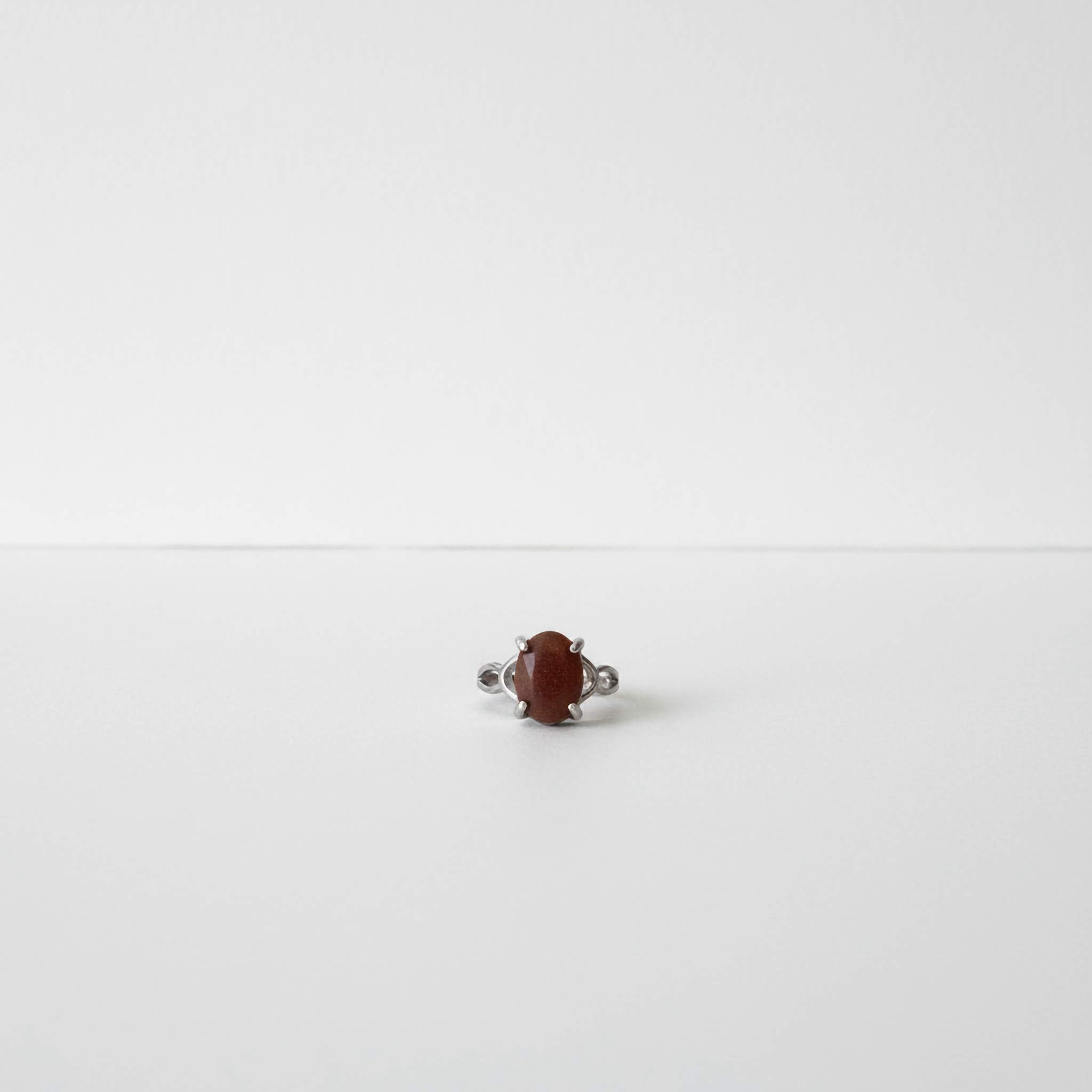 Silver ring with a brown gemstone on a white background