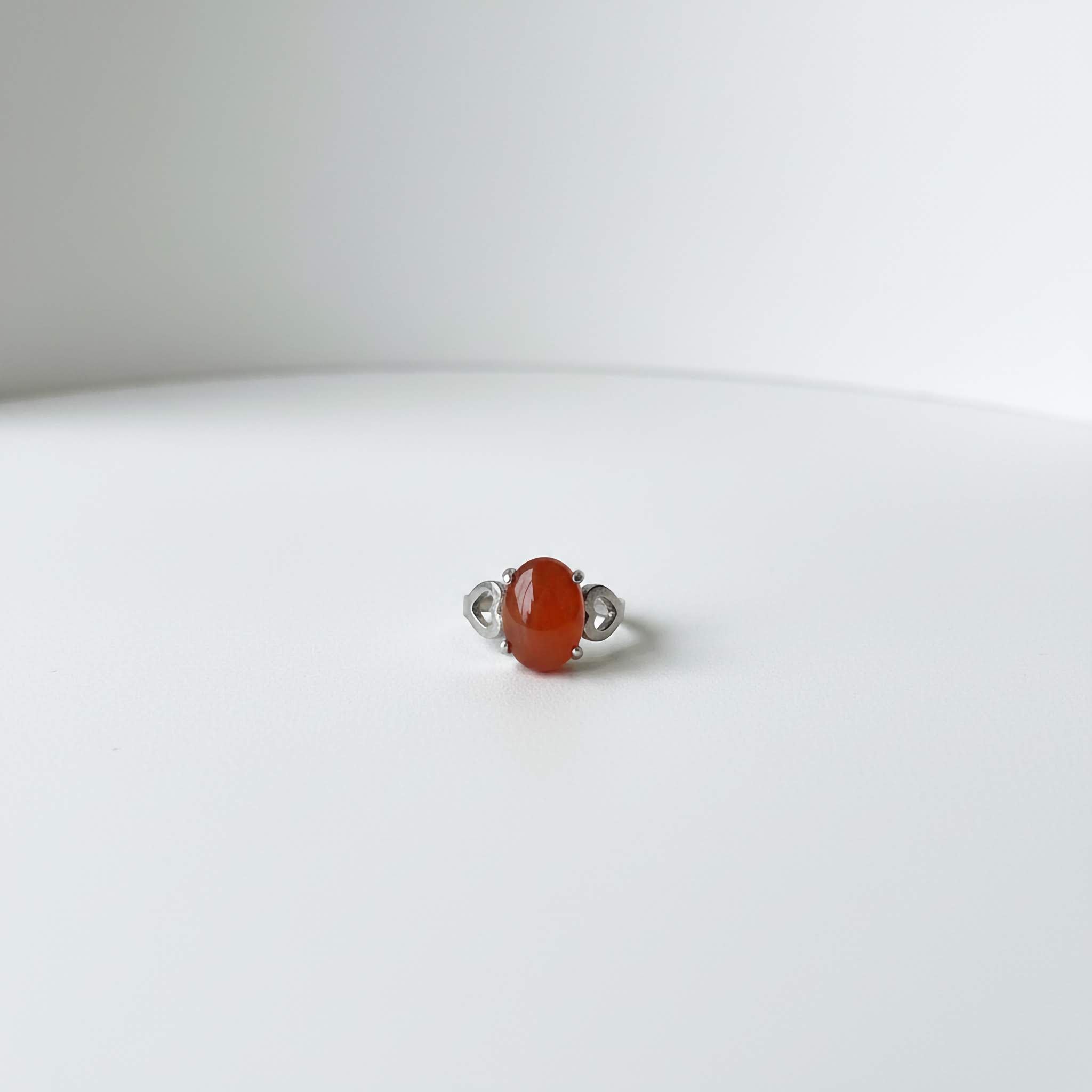 Silver ring with a maroon stone on a white background