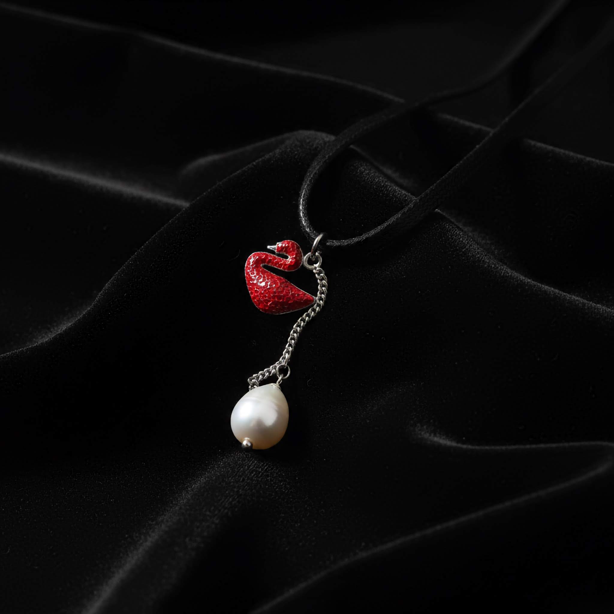Pearl necklace with a pink teardrop pendant on a white surface