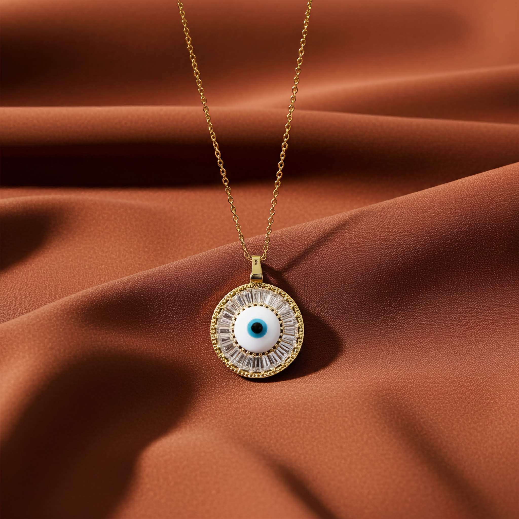 A evil eye Gold necklace with an eye-shaped pendant on a brown fabric background