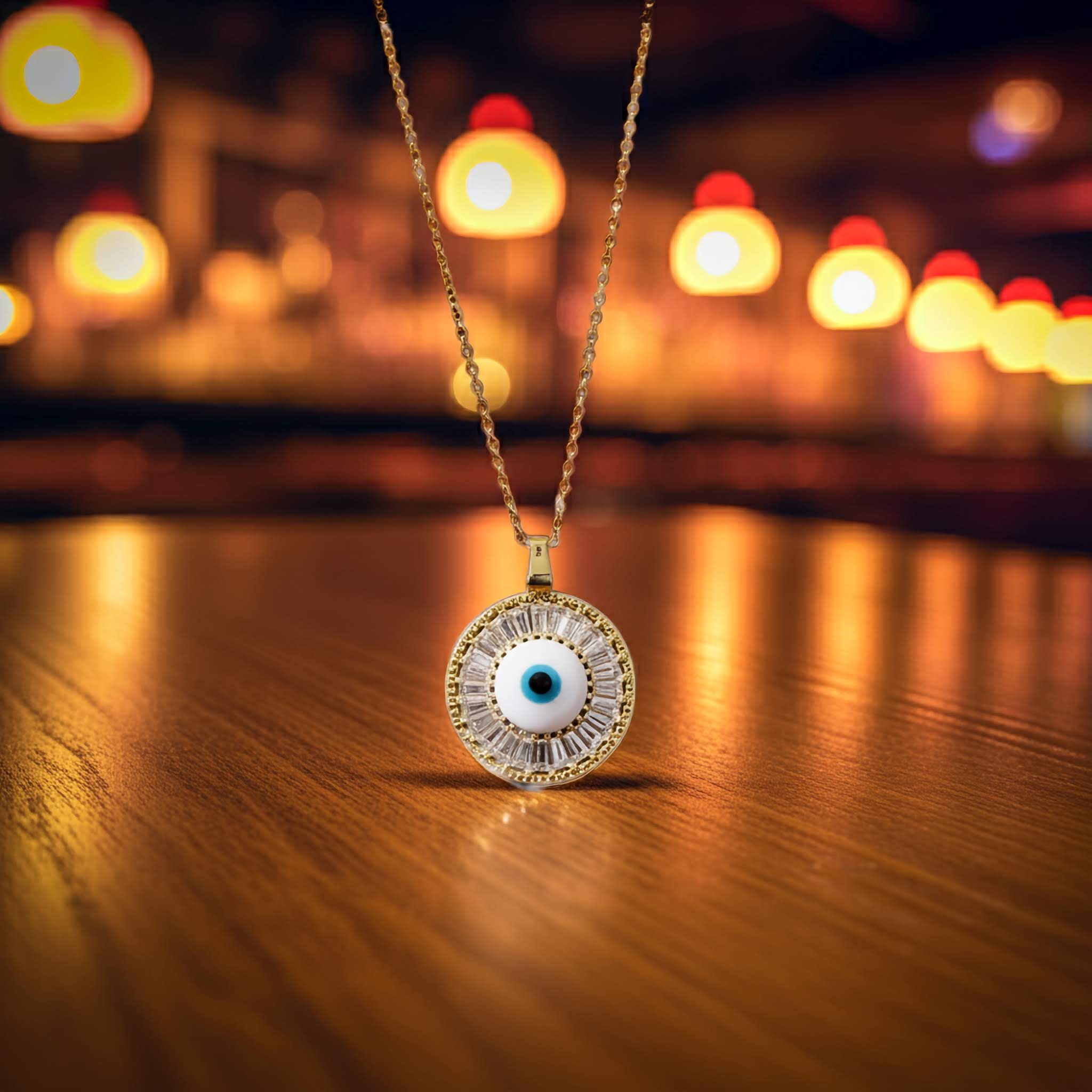 A Evil eye Gold necklace with an eye-shaped pendant on a wooden surface with blurred lights in the background