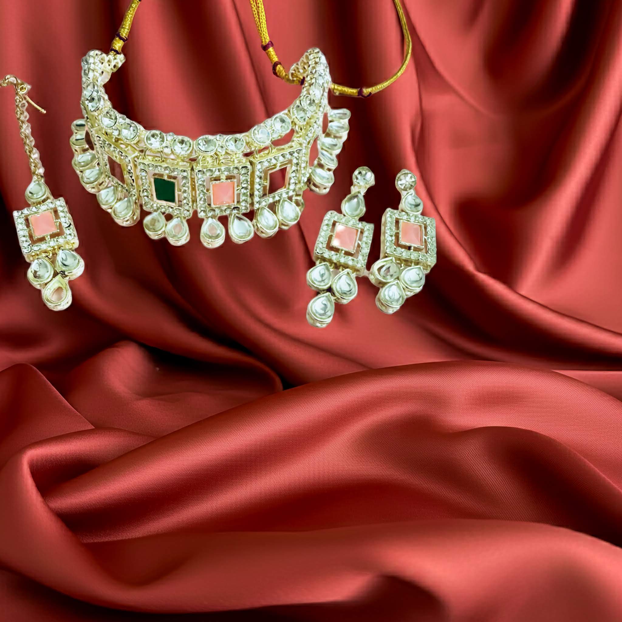 Silver kundan choker with pink stones on it set with  earrings on red fabric
