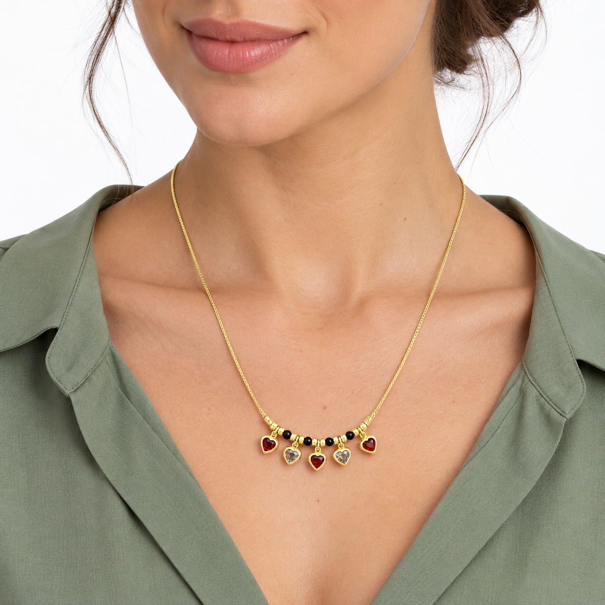 Model wearing LeDeSaRa gold-tone red and clear heart charm necklace with a sage blouse