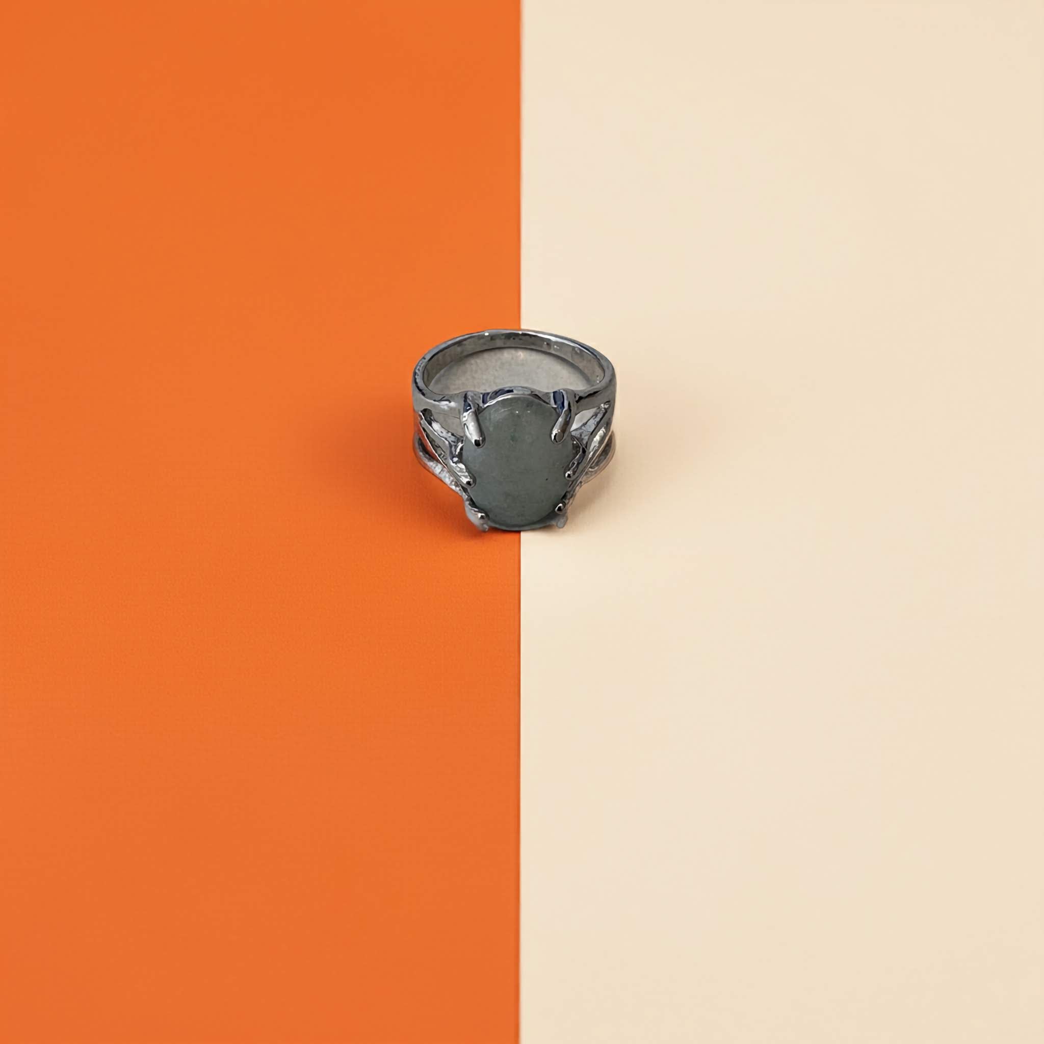 light green gemstone in Silver ring on an orange and beige background