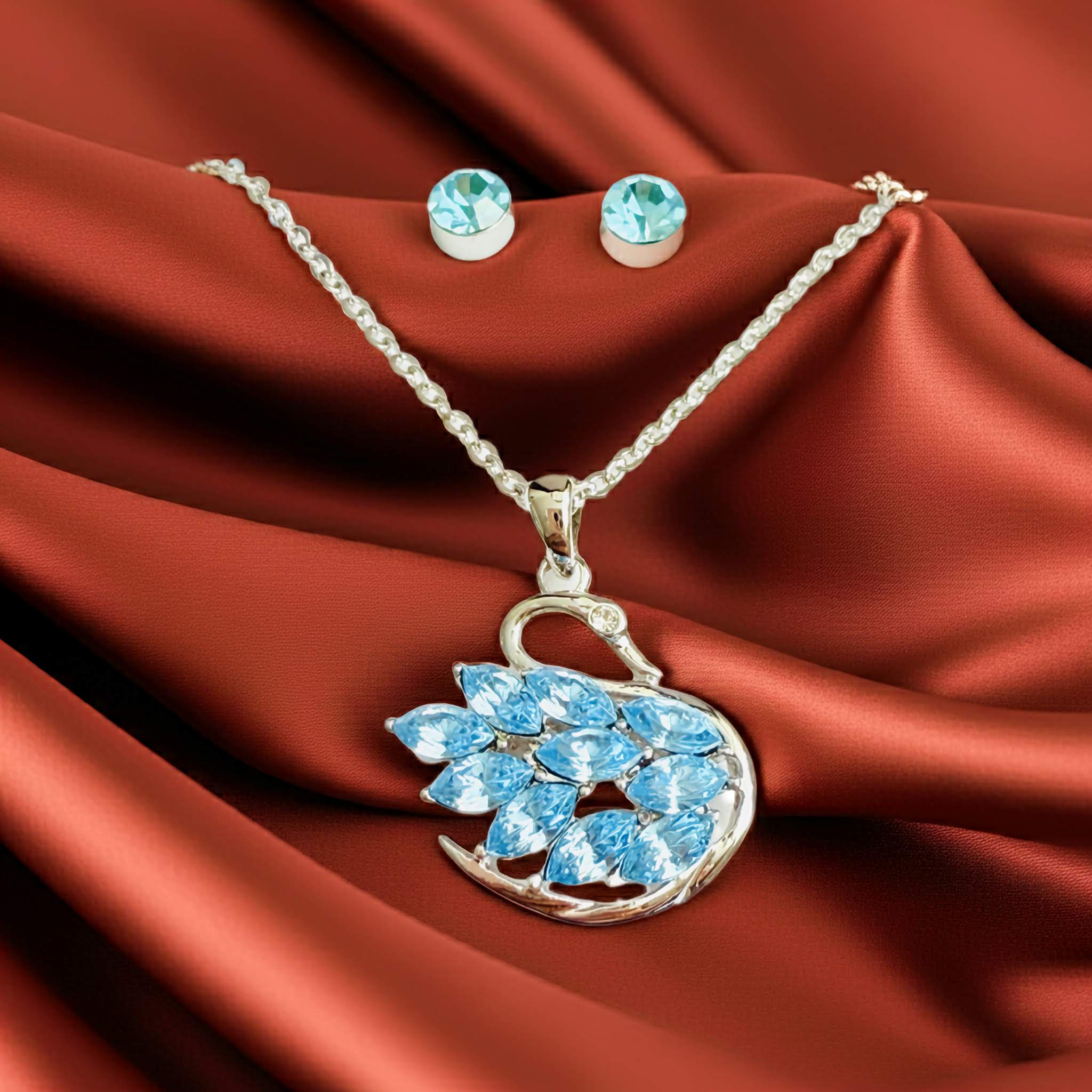 A Swarovski inspired Jewelry set with a swan-shaped pendant and matching earrings on a red satin background